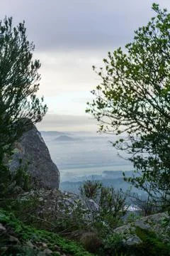 View from behind the rocks and trees to the hills, forests and fields in the Stock Photos