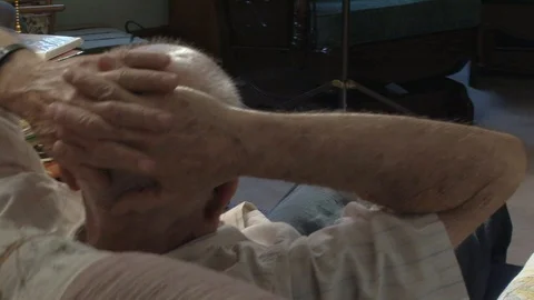 View from behind of senior rubbing head while in a rocking armchair Stock Footage 105756762