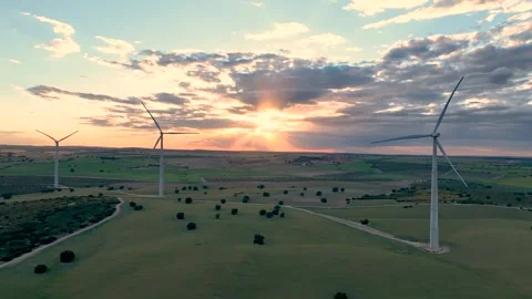 View from behind from a static point of three wind turbines in line rotating Stock Footage 274528145