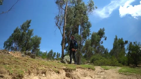 View from behind of a white man with black clothes and backpack hiking through Vidéo 164593498