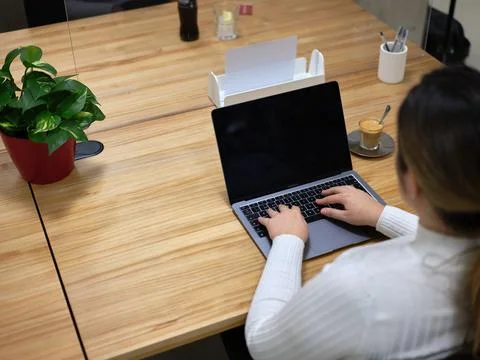 View from behind of a woman using her laptop in a coworking space Stock Photos