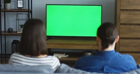 View from behind on the young man and woman sitting on the couch in the living 스톡 동영상 90206205