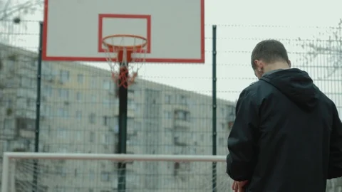 View from behind the young man throwing the ball into the basketball hoop 스톡 동영상 106234600