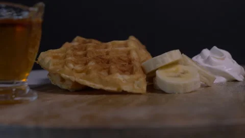 View of Belgian Waffles, Maple Syrup. Banana Slices and Whipped Cream Stock Footage 130833867