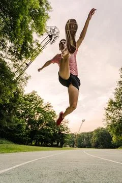 View from below of an athlete running fast in a race on the athletics track Stock Photos