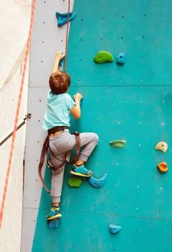 View from below of the boy grab rock climb wall Stock Photos