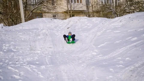 View from below on a boy sledding. Cute child riding from snow slide in winter. Stock Footage 118750697