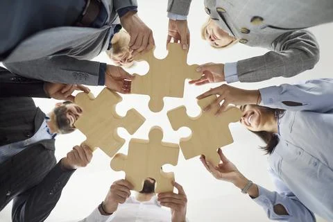 View from below of business people assemblling pieces of puzzle, finding 스톡 사진