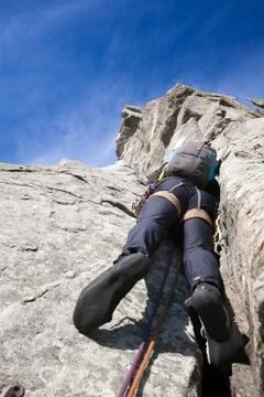 View from below of a climber while climbing a steep rock wall Foto stock