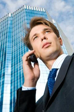 View from below of confident businessman speaking on the phone outdoors Stock Photos