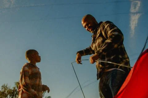 View from below of dad and son enjoying putting up a camping tent Foto stock
