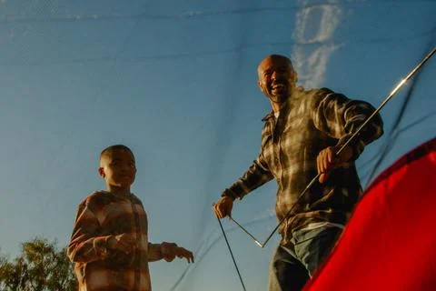 View from below of dad and son enjoying putting up a camping tent Stock Photos