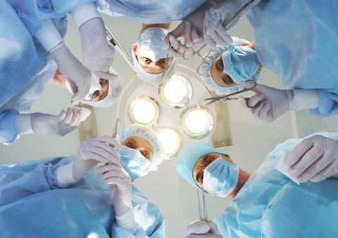 View from below of experienced surgeons with medical tools during operation Stock Photos