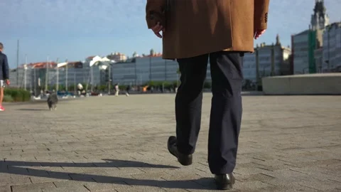 The view from below at the floor, from behind the man walks forward in pants and Stock Footage 220320961