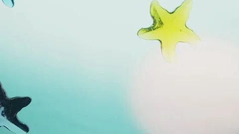 View from below as a hand pours artificial colored starfish. Background for the Stock Footage 122591052
