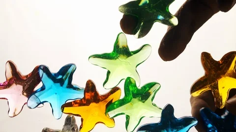 View from below as a hand pours artificial colored starfish. Background for the Stock-Footage 122592727
