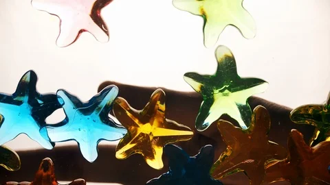 View from below as a hand pours artificial colored starfish. Background for the Stock Footage 122594151
