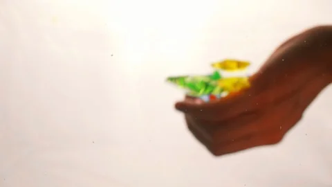 View from below as a hand pours artificial colored starfish. Background for the Stock-Footage 122595656