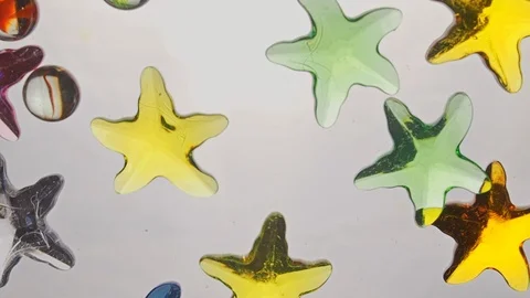 View from below as a hand pours artificial colored starfish. Background for the Stock-Footage 122596794