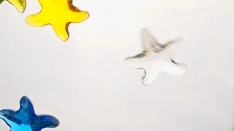 View from below as a hand pours artificial colored starfish. Background for the Stock Footage 122606769