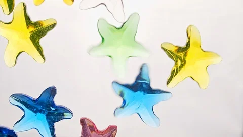 View from below as a hand pours artificial colored starfish. Background for the Stock-Footage 122607109