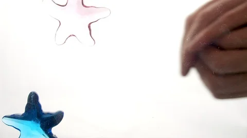 View from below as a hand pours artificial colored starfish. Background for the Stock Footage 122617806