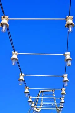 View from below of light bulbs in line with blue sky background Stock Photos