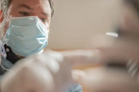 View from below of a man wearing a flu mask looking at mobile phone Stock Photos