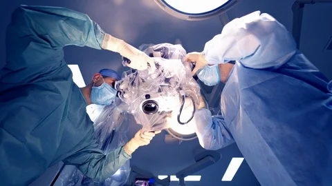 View from below on a microscope and two specialists looking inside. Neurosurgeon Stock Footage 118215301