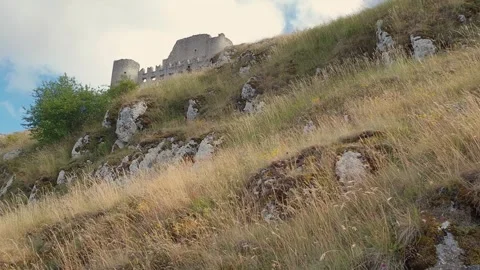 View from below of people walking toward rocca calascio castle Stock Footage 279843517