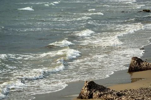 View from below of sandy beach and waves at sunset Stock Photos