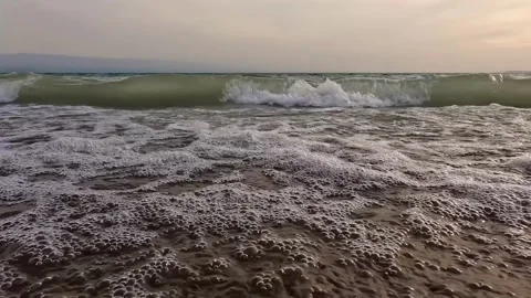 A view from below as waves roll onto a sandy beach and create foam Stock-Footage 317168322