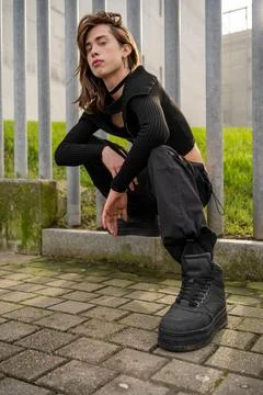 View from below of young man with long hair and dark clothes. Stock Photos