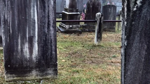 View Between Old, Weathered Headstones (Tombstones) in Rainy Cemetery Stock Footage 101308961