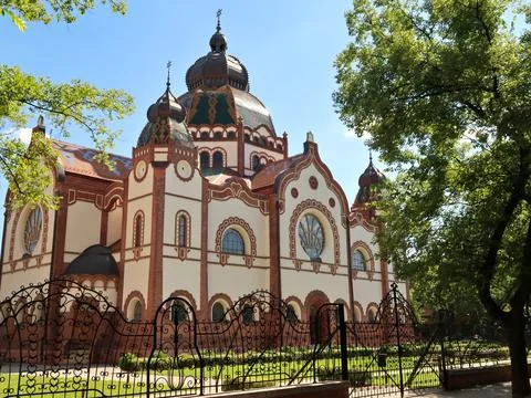 View between trees onto the Synagogue of Subotica behind a black metal fenc.. Foto stock