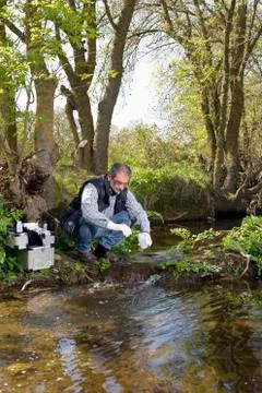 View of a Biologist take a sample in a river. Stock Photos