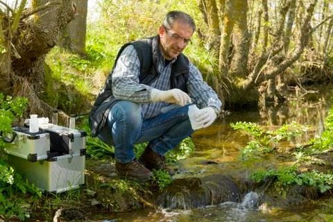View of a Biologist take a sample in a river. Stock Photos