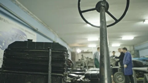 View of black steering rack and black containers inside of workshop with men on Stock-Footage 97745965