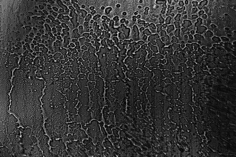 View on a black-white background with the texture of flowing drops of water o Stock Photos