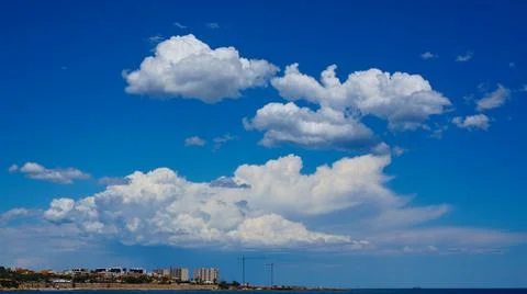 View to blue big white clouds on blue sky above coast Stock Photos