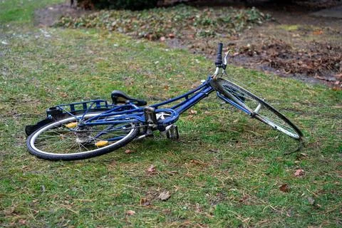 View of a blue broken bicycle lying on green grass Fotos de archivo