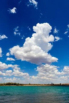 View of blue cloudy sky over the steppe river with a calm current Stock Photos