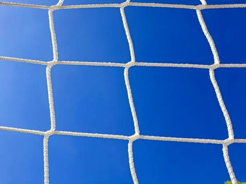 View of the blue sky from behind the net in a football goal 스톡 사진