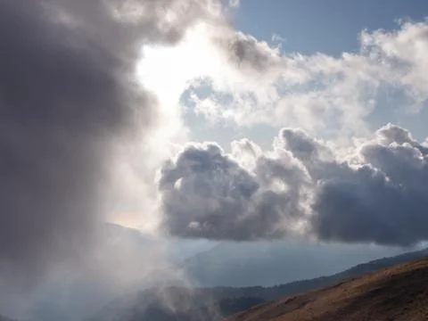 View of blue sky clouds and mountains through a light misty haze Stock Photos
