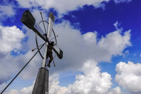 View to the blue sky with clouds and a wonderful summit cross Stock Photos