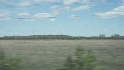 View of the blue sky with clouds, fields, and forests from the side window of a Stock Footage 194476381