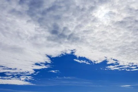 View of blue sky with white clouds forming textured pattern across horizon. Stockfoto's