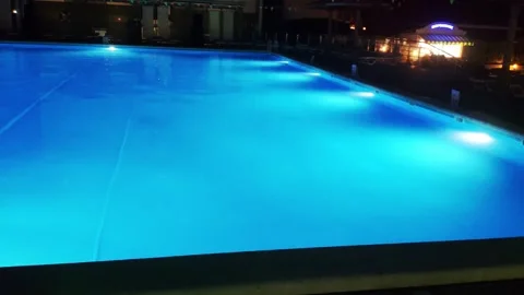 View of the blue swimming pool at night with lights in the hotel Stock Footage 295603323