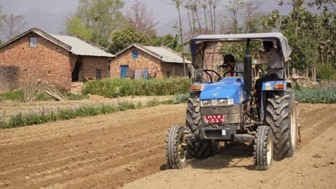 View of a blue tractor plowing a field in Dhangadhi, Nepal. Stock Footage 335473485