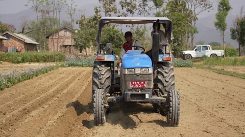 View of a blue tractor plowing a field in Dhangadhi, Nepal. Video stock 335473530